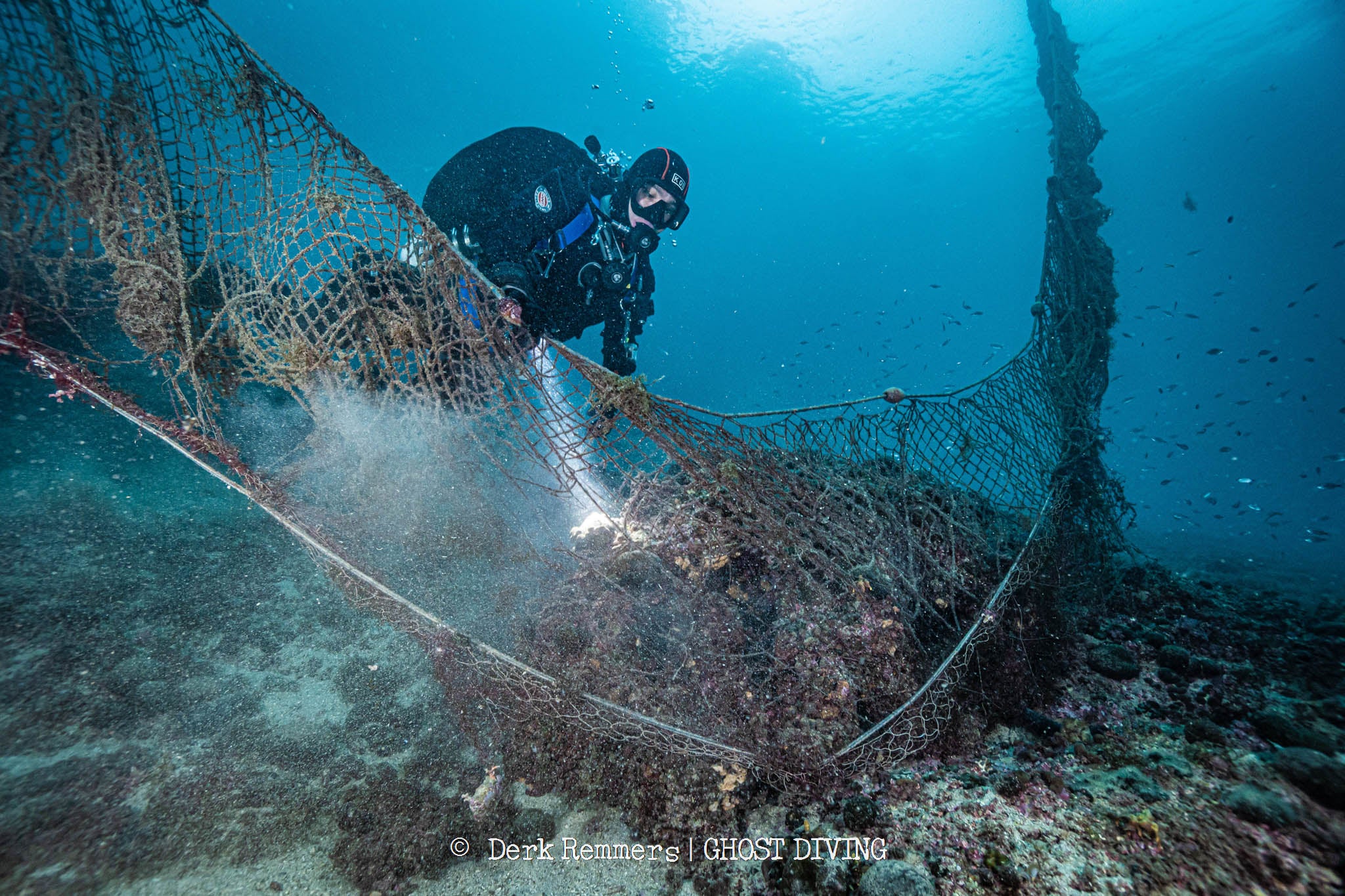 Taucher, der ein Fischernetz im Meer begutachtet